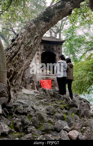 HANOI, VIETNAM - le 21 janvier 2016 : deux écolières de donner des offrandes et priant pour les résultats de l'examen avec succès à un petit sanctuaire n Banque D'Images