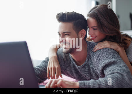 Jeune couple shopping online à la maison sur ordinateur portable Banque D'Images