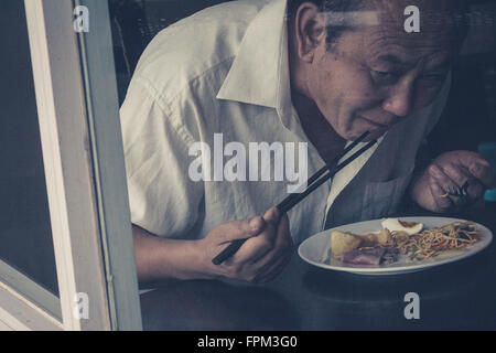 Saigon, Vietnam - Février 11, 2014 : Portrait d'un vieil homme prendre le petit déjeuner dans un restaurant. Banque D'Images