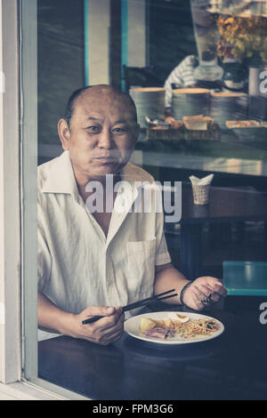 Saigon, Vietnam - Février 11, 2014 : Portrait d'un vieil homme prendre le petit déjeuner dans un restaurant. Banque D'Images