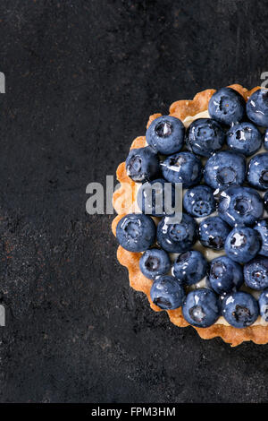 Tartelette au citron avec des bleuets frais sur fond noir. Vue d'en haut. Avec un espace réservé au texte Banque D'Images