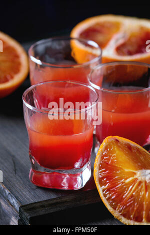 Close up of Short cocktail d'alcool avec des tranches d'orange sanguine de Sicile et le jus d'orange rouge frais, servis sur l'onglet en bois noir Banque D'Images