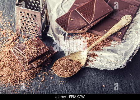 Le chocolat. Chocolat noir. Quelques cubes de chocolat noir. Plaques de chocolat râpé déversés par le chocolat en poudre. Les grains de café. Banque D'Images