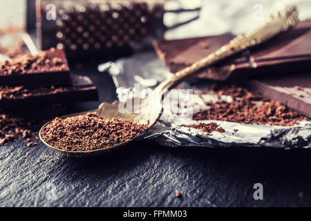 Le chocolat. Chocolat noir. Quelques cubes de chocolat noir. Plaques de chocolat râpé déversés par le chocolat en poudre. Les grains de café. Banque D'Images