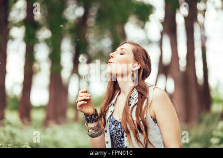 Woman blowing dandelion dans l'air Banque D'Images