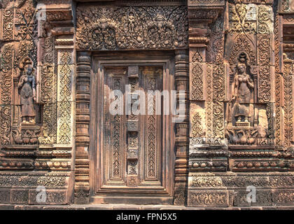 Fausse porte et devatas, demi-déesses, de chaque côté d'un mur sculpté orné, de grès rose dans la citadelle des Femmes Banque D'Images