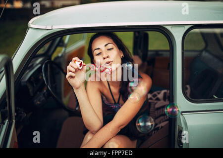 Femme souffle des bulles de savon dans l'air, Banque D'Images