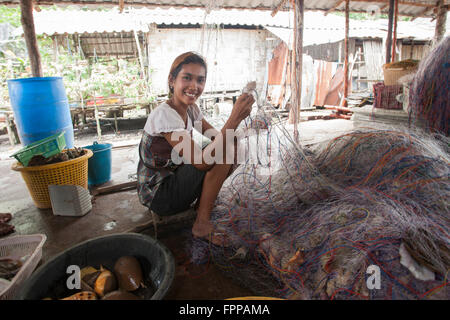 Femme thaïlandaise réparant un filet de pêche, village flottant, baie de Phang Nga, Phuket, Thaïlande Banque D'Images