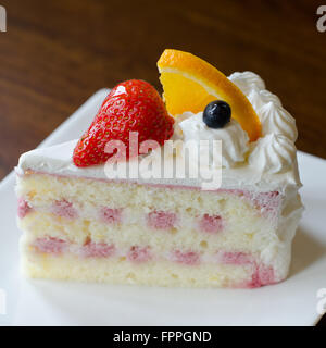 Part de tarte avec la crème pudding et de fraise mûre et orange sur une plaque Banque D'Images