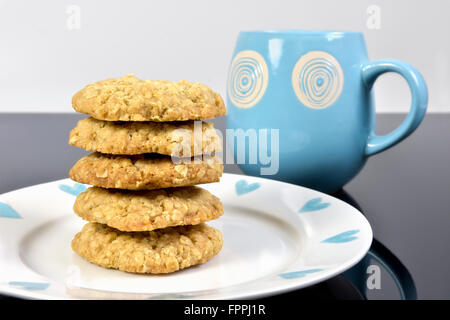 Des tas d'avoine fait maison les cookies sur la plaque sur le travail noir avec haut bleu mug Banque D'Images