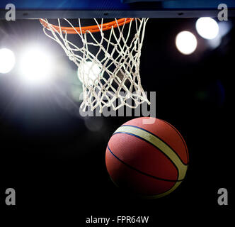 Le basket-ball en passant par le cercle à une arène de sports (intentionnel) spotlight Banque D'Images