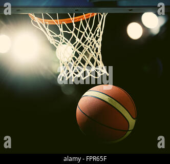 Le basket-ball en passant par le cercle à une arène de sports (intentionnel) spotlight Banque D'Images