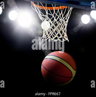 Le basket-ball en passant par le cercle à une arène de sports (intentionnel) spotlight Banque D'Images