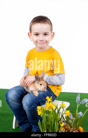 Jeune garçon avec des fleurs de printemps et de lapin sur fond blanc. Banque D'Images
