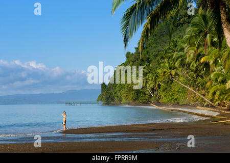 Figure sur une plage de sable noir volcanique sauvage et déserte dans le Golfo Dulce, Golfito, Puntarenas, Costa Rica, Amérique centrale Banque D'Images