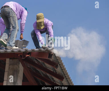 Les travailleurs de la construction de l'installation des tuiles du toit pour la construction Banque D'Images