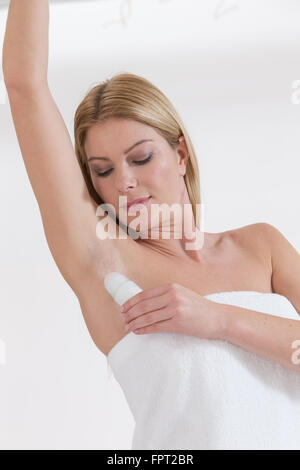 Young woman applying deodorant Banque D'Images