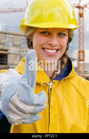 Jeune femme sur un chantier avec thumb up Banque D'Images