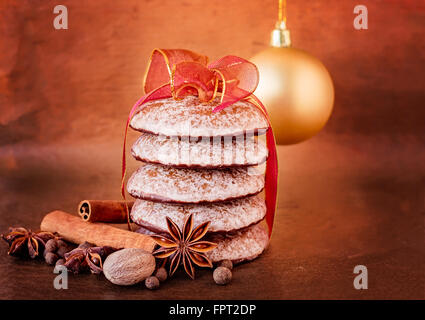 Ruban noué gingerbread cookies au chocolat avec des épices et une boule de noël en arrière-plan. Banque D'Images