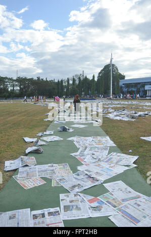 Une mère et son fils marchant sur les feuilles de papier journal que Eid-Al-Fitr utilisé pendant à Makassar, Indonésie, 17 juillet 2015 o Banque D'Images