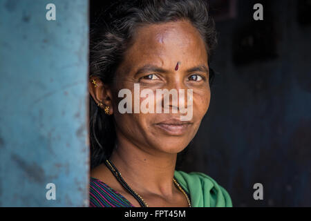 Femme indienne élégant habillé en vert sari à un mur rond bleu à l'extérieur de la maison rurale Banque D'Images