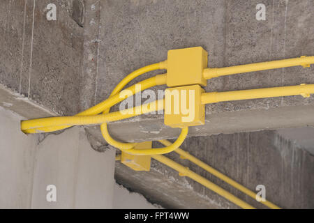 Les tuyaux en PVC jaune pour les boîtes électriques et les câbles enterrés sur mur de béton at construction site Banque D'Images