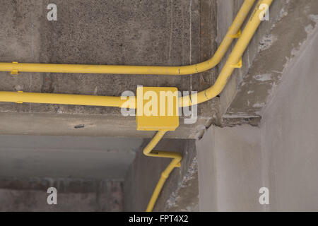 Les tuyaux en PVC jaune pour les boîtes électriques et les câbles enterrés sur mur de béton at construction site Banque D'Images