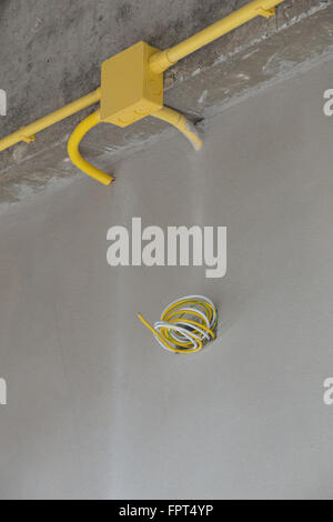 Les tuyaux en PVC jaune pour les boîtes électriques et les câbles enterrés sur mur de béton at construction site Banque D'Images