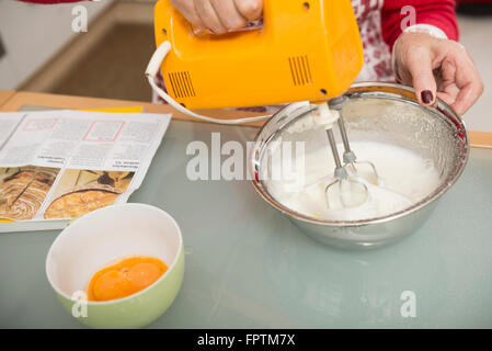 Senior woman meringue mélanger dans un bol à mélanger en cuisine, Munich, Bavière, Allemagne Banque D'Images