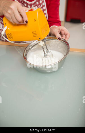 Senior woman meringue mélanger dans un bol à mélanger en cuisine, Munich, Bavière, Allemagne Banque D'Images