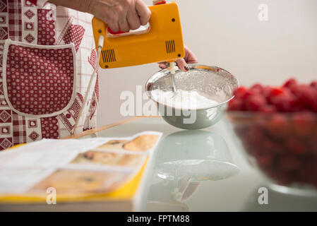 Senior woman meringue mélanger dans un bol à mélanger en cuisine, Munich, Bavière, Allemagne Banque D'Images