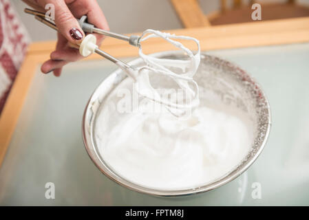 Senior woman holding fouet sur bol rempli de meringue, Munich, Bavière, Allemagne Banque D'Images