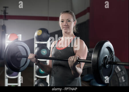 Jeune femme dans la salle de sport de la tige de levage pour l'exercice d'haltères biceps, Bavière, Allemagne Banque D'Images