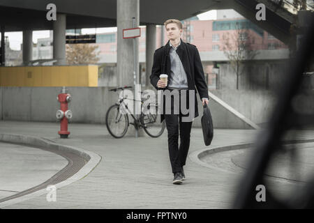 Teenage businessman holding briefcase bureau va et tasse à café, Bavière, Allemagne Banque D'Images