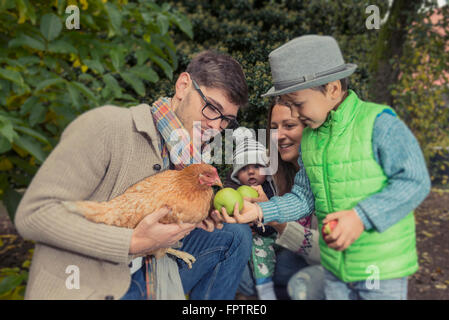 Père tenant un oiseau poulet et fils apple alimentation, Bavière, Allemagne, Banque D'Images