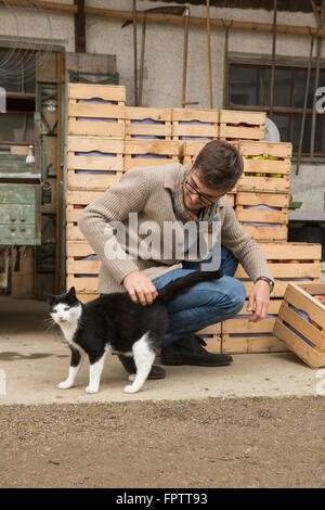 Mid adult man caresser chat noir dans ferme, Bavière, Allemagne Banque D'Images