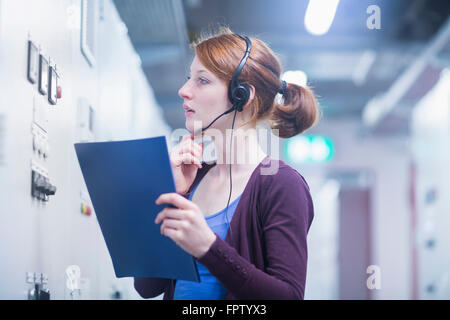Jeune femme de l'ingénieur maîtrise d'un dispositif de commutation dans la salle de commande, Bade-Wurtemberg, Allemagne Banque D'Images