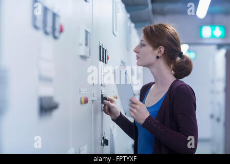 Jeune ingénieur femelle panneau de mise à jour par tablette numérique dans une industrie, Freiburg im Breisgau, Bade-Wurtemberg, Allemagne Banque D'Images