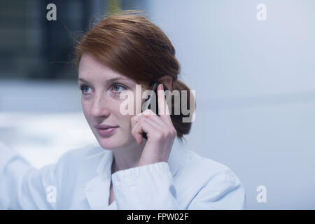 Jeune ingénieur en conversation sur un téléphone mobile près de l'appareillage dans une industrie, Freiburg im Breisgau, Bade-Wurtemberg, Allemagne Banque D'Images