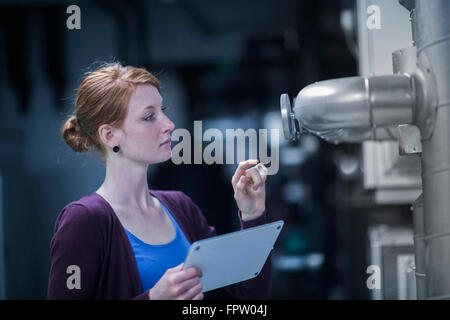 Jeune femme un appareillage de contrôle de l'ingénieur dans la salle de commande, Freiburg im Breisgau, Bade-Wurtemberg, Allemagne Banque D'Images