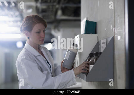 Jeune ingénieur contrôle de bouteilles chimiques femelle dans un rack, Freiburg im Breisgau, Bade-Wurtemberg, Allemagne Banque D'Images