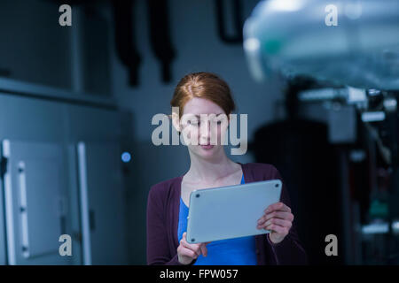 Les jeunes filles à l'aide d'une tablette numérique ingénieur dans une usine industrielle, Freiburg im Breisgau, Bade-Wurtemberg, Allemagne Banque D'Images