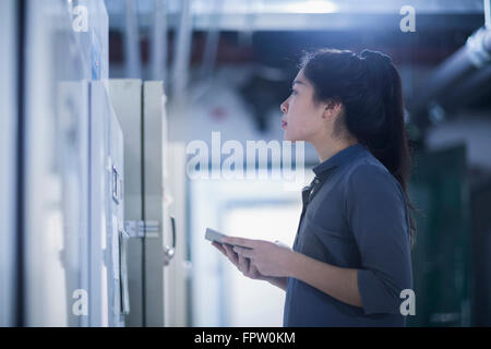 Jeune ingénieur femelle panneau de mise à jour par tablette numérique dans une industrie, Freiburg im Breisgau, Bade-Wurtemberg, Allemagne Banque D'Images
