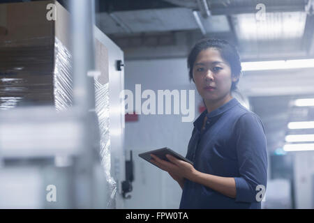 Jeune ingénieur femelle panneau de mise à jour par tablette numérique dans une industrie, Freiburg im Breisgau, Bade-Wurtemberg, Allemagne Banque D'Images
