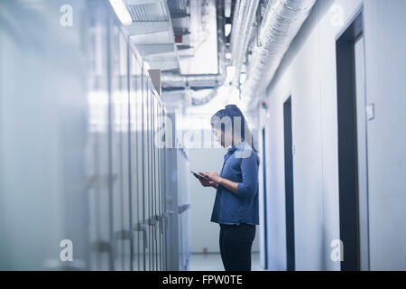 Jeune ingénieur femelle panneau de mise à jour par tablette numérique dans une industrie, Freiburg im Breisgau, Bade-Wurtemberg, Allemagne Banque D'Images