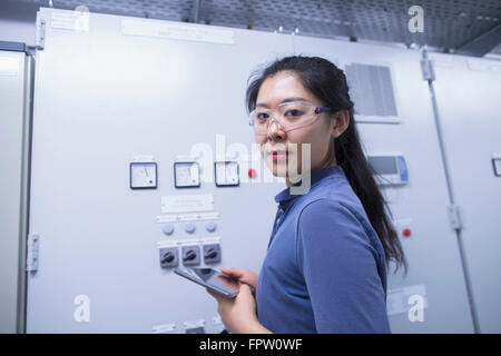 Jeune ingénieur femelle panneau de mise à jour par tablette numérique dans une industrie, Freiburg im Breisgau, Bade-Wurtemberg, Allemagne Banque D'Images