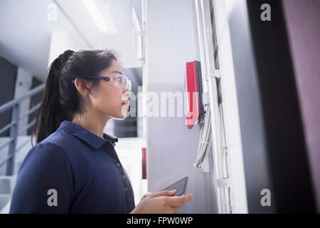 Jeune ingénieur femelle panneau de mise à jour par tablette numérique dans une industrie, Freiburg im Breisgau, Bade-Wurtemberg, Allemagne Banque D'Images