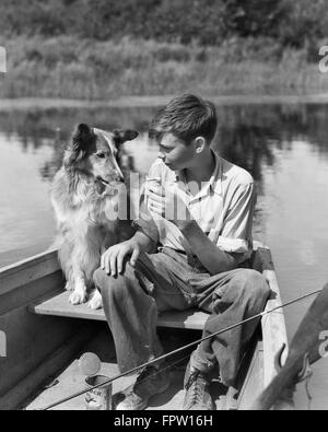 1930 GARÇON ET COLLEY CHIEN ensemble en barque avec Canne à pêche d'embrouilles SUR LE PARTAGE DE L'ALIMENTATION DE L'ÉTANG DE CRÈME GLACÉE Banque D'Images