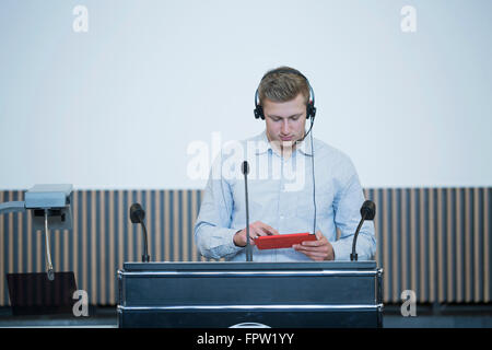 Jeune étudiant debout à lutrin et travailler sur une tablette numérique tout en donnant lecture, Bade-Wurtemberg, Allemagne Banque D'Images