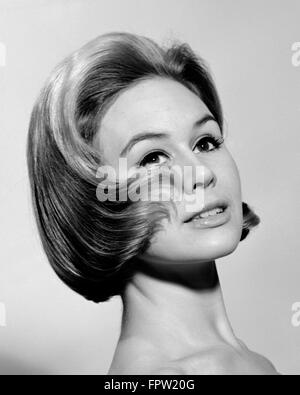 1960 FASHION PORTRAIT DE FEMME AVEC CHEVEUX CURLING SUR SA JOUE Banque D'Images